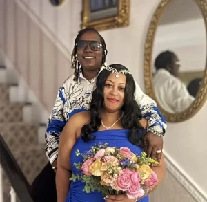 Two women in blue and standing on a stair case with flowers and sun glasses