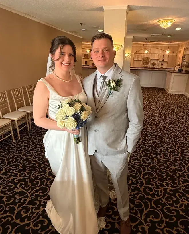 Bride and groom smiling with their bouquet after the ceremony