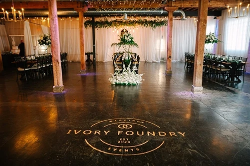 Ivory Foundry wedding reception hall with logo on dance floor and elegant floral decor in Indianapolis Indiana — wedding coordination by Weddings by Bretta