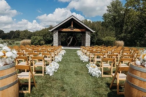 Outdoor wedding ceremony setup with wooden chairs and white floral aisle at The Sycamore at Mallow Run, coordinated by Weddings by Bretta Indianapolis wedding planner