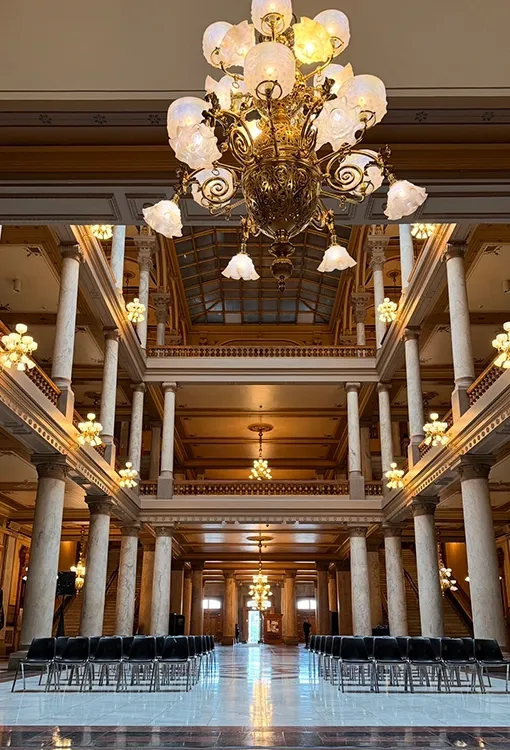 Grand event hall with marble columns, ornate gold chandeliers, and rows of chairs set for a micro wedding ceremony Grand event hall with marble columns, ornate gold chandeliers, and rows of chairs set for a micro wedding ceremony